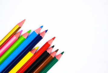 Fototapeta premium Some different colored wood pencil crayons scattered on a white background