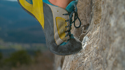 MACRO: White magnesium powder is smeared on the rock as woman edges up a cliff.