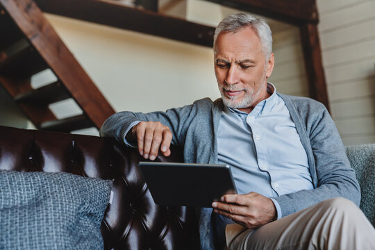 Mature caucasian man websurfing on digital tablet at home