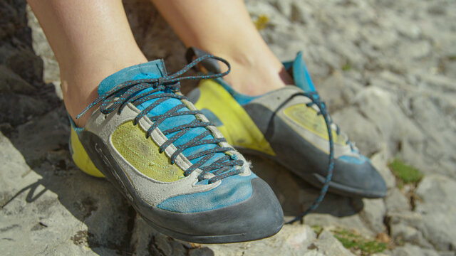 CLOSE UP: Woman on rock climbing trip gets ready for ascent by tying her shoes.