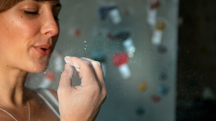 CLOSE UP: Young woman blows excess magnesium off her fingertips while climbing.