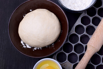 Dough and utensils for making dumplings against the dark background	
