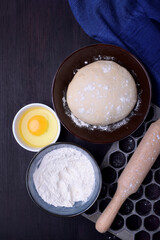 Dough and utensils for making dumplings against the dark background	