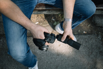 Top view of cropped photographer removing camera's flash. Close-up view of male's hands removing flash from professional camera outdoor .