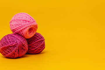 lilac, pink balls of wool lie on a yellow background