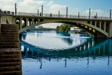 A view down the east bank of the river Guadalquivir under the San Telmo bridge in Seville, Spain in the summertime