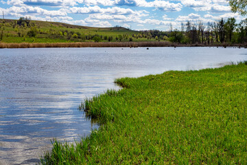 Blue lake on the background of green slopes in the village