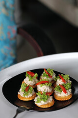 Tuna salad with crackers on black dish. Canape tuna.