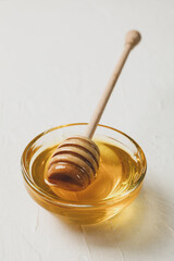 Bowl with honey and dipper on white background