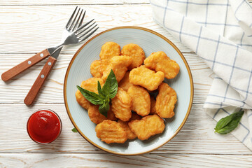 Composition with plate of chicken nuggets on white wooden background