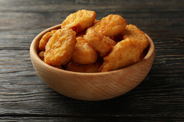 Bowl with fried chicken nuggets on wooden background