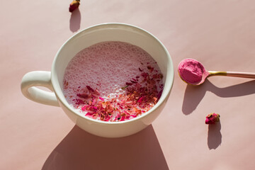 Cup of rose cardamom ayuverdic drink on pink background.