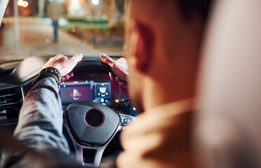 Handsome unshaved man in fashionable clothes riding his automobile