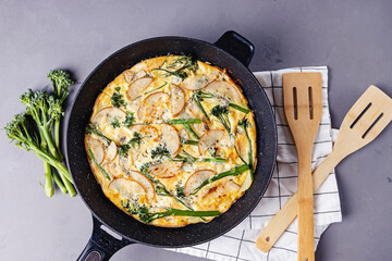 Baked egg frittata with cheese and broccolini on grey table