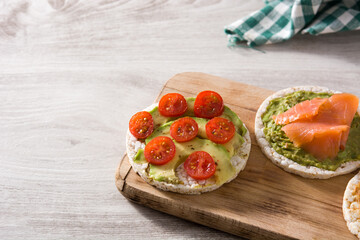 Assortment of ingredients on puffed rice cakes on white wooden table. Copy space