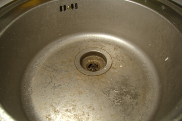Dirty round stainless steel kitchen sink. Sloppy, ungroomed. Poor housekeeping