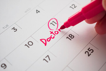 important doctor appointment schedule write on white calendar page date close up