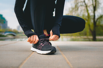 closeup view of woman's hands in sport suit tying up shoelaces on her sport sneakers while running...