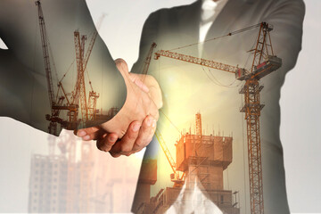 Double exposure of businesswomen double handshake, construction crane, bulilding and sunlight of...