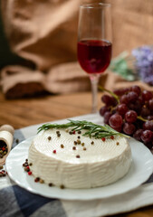 Goat cheese, grapes and wine lie on a wooden table. Cheese at home.