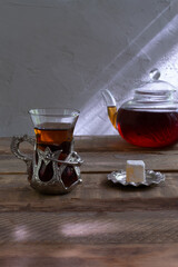 Turkish tea in a traditional cup with a glass teapot on a wooden table. Tea drinking with oriental sweets and a hot drink. Copy space.