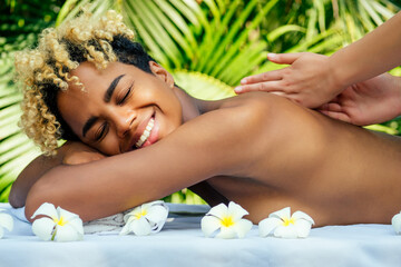 Obraz na płótnie Canvas attractive african american female get treatment massage in tropics resort outdoor salon