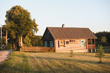 Obraz premium old wooden house in village. Farmhouse in Belarus. View of rustic ethnic house on sunset. rural landscape