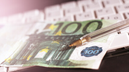 One bill of one hundred of euros on the laptop's keyboard