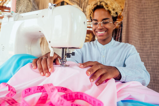 brazilian designer female with cute blonde afro curls hair making handmade clothes in her tropical eco house in Bali