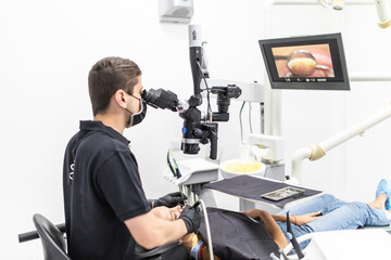 The dentist examines the patient's teeth with a dental microscope. Modern medical equipment