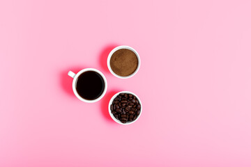 coffee beans, ground and black coffee or espresso in mugs on a pink background. concept of making coffee. coffee shop or store concept. flat lay, top view, minimalism.