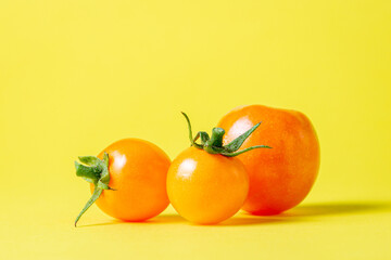Yellow tomatoes on a yellow background. Ripe juicy tomatoes. Tomato variety