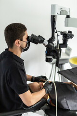 Male dentist examining senior woman looking on the teeth with professional microscope in dental office