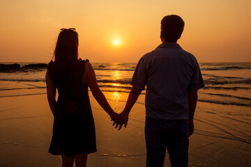 Vacation couple walking on beach together in love at sunset goa