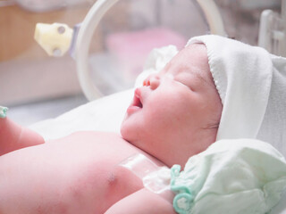 Newborn baby girl inside incubator in hospital post delivery room