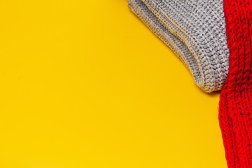 part of a grey sweater and red scarf on a yellow background, copy space