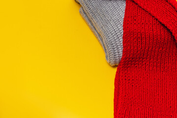part of a grey sweater and red scarf on a yellow background, copy space