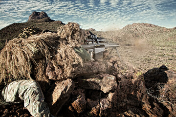 Military operator downrange taking a shot from a sniper rifle in the mountains.