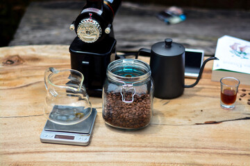 Traditional coffee tools, consisting of a coffee grinder, glass cup, teapot and coffee beans on an antique wooden table