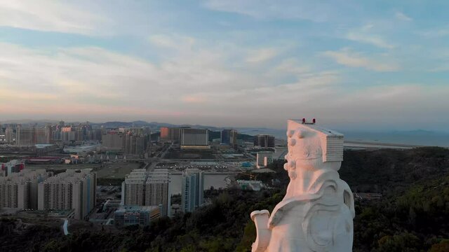 Rising aerial behind famous Goddess A-Ma Statue during golden hour sunset