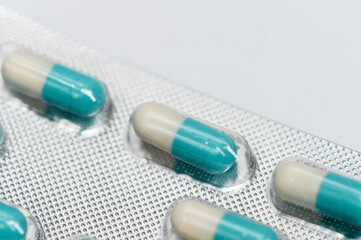 Blue and white pills capsules in blister on white background. Isolated. Selective focus. Close up. Concept pharmacy, medicine, healthcare, painkillers, drug, abuse