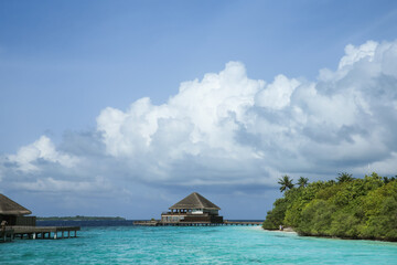 Maldives sea, clouds, palms and villas.