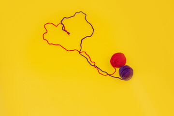 heart of red and blue thread, unraveled from a tangle on an orange background