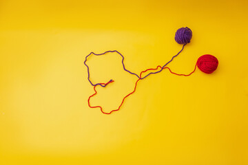 heart of red and blue thread, unraveled from a tangle on an orange background