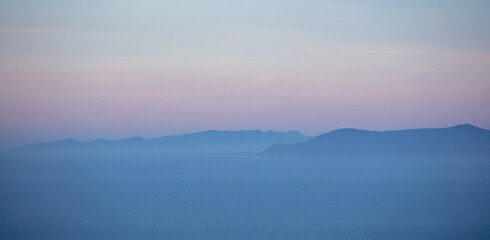 Aegean sea and Attica Greece hills, pastel blue and pink shades on sea and sky background,