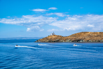 Fototapeta na wymiar Inflatable speed boats cruising in mediterranean sea. Lighthouse on a cape. Greece, Kea Tzia island.
