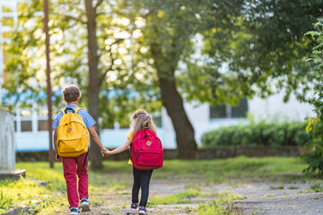 Primary school pupil. boy and a girl with backpacks are walking down the street.