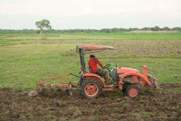 Obraz premium Tractor working plows a field on the farm for planting.