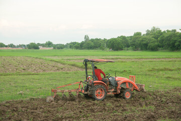 Fototapeta premium Tractor working plows a field on the farm for planting.