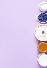 Cream, blueberries, cottage cheese, milk and honey on a pink background copy space